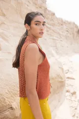 Top tejido color beige con espalda calada y cuello mao. Presenta cierre frontal con cordones y detalle de broches decorativos en el cuello.