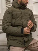 Campera verde militar con capucha, cierre frontal con cremallera y broches, bolsillos laterales con solapa y puños ajustables con velcro.