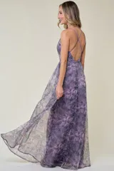 Vestido largo de fiesta con estampado floral en tonos grises, negros y rosados. Tiene escote en V, tirantes finos y falda amplia de organza.