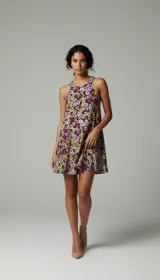 Vestido corto con estampado floral multicolor en tonos violetas, amarillos y rosados. Tiene escote halter, bolsillos laterales y corte suelto.