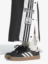 Falda larga Adidas Adicolor, color negro, de tejido de tricot brillante. Diseño inspirado en el pantalón deportivo Adibreak, con corte holgado, largo maxi y botones a presión laterales con logo de la marca. Confeccionada con materiales 100% reciclados.