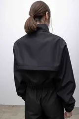 Campera cropped de inspiración deportiva, color azul marino, con cuello alto, cierre frontal a tono, bolsillos funcionales y puños elastizados. Confeccionada en tela campera repelente al agua, con interior de micropolar.