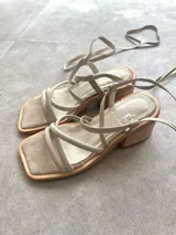 Sandalias plateadas con tiras finas cruzadas y tobilleras con cordones. Tacón de madera.