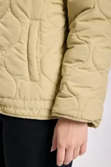 Campera capitoneada color verde claro, con capucha y cierre frontal con botones a presión. Tiene bolsillos laterales y cordón ajustable en el ruedo.