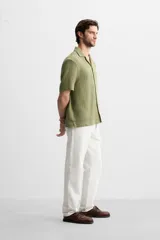 Camisa verde oliva de manga corta con cuello bowling, corte relaxed fit y cierre frontal con botones.