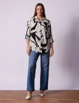 Camisa de manga larga con estampado abstracto en tonos verde y blanco. Cuello con solapa y abertura central con botones. Largo de manga regulable con presilla y botón. Terminación de ruedo anudada opcional.