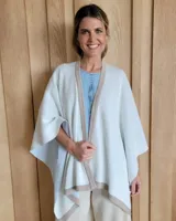 Ruana negra de tejido de punto con una estrella grande color beige en la espalda y borde inferior con franja beige.