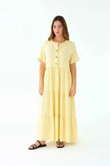 Vestido largo amarillo de lino, corte amplio, con cuello mao, mangas cortas y falda escalonada con volados.