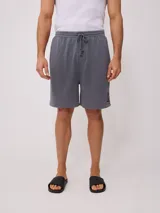 Short gris de felpa con corte holgado, cintura elastizada con cordón ajustable y logo estampado en la pierna.