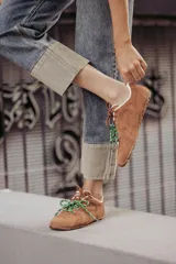 Zapatillas urbanas de cuero color tostado, con cordones verdes y suela de goma.