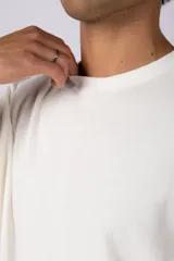 Remera de hombre color crudo, corte oversize, confeccionada en algodón grueso con textura micropanal. Diseño liso sin logos, con costura en forma de 'X' en la espalda. Ideal para un look casual y relajado.