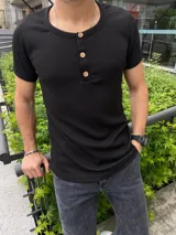 Remera negra de corte ajustado, cuello redondo con abertura de botones de madera y mangas cortas.