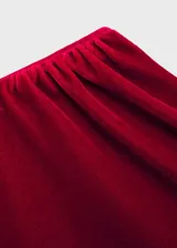 Top de terciopelo rojo con un solo hombro, manga larga y frunces laterales.