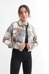 Chaqueta corta a cuadros grises, marrones y blancos, con cuello clásico, cierre abotonado, mangas largas y dos bolsillos con solapa en el pecho.
