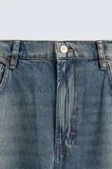 Pantalón de jean celeste con efecto lavado, corte amplio tipo balloon fit, tiro medio, cinco bolsillos y cierre frontal con cremallera y botón.