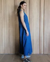 Vestido largo color crudo, sin mangas y con escote en V. Presenta aberturas laterales en el ruedo y bolsillos laterales a la altura de la cadera.