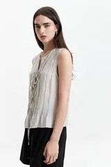 Blusa sin mangas color beige con lazo frontal y textura liviana.
