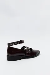 Zapato tipo zueco negro charol con punta fina, doble tira con hebillas metálicas y pulsera al tobillo con tachas.