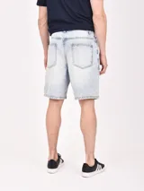 Bermuda de jean negro con roturas y corte a la rodilla.