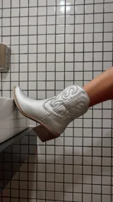 Bota corta plateada de estilo texano con bordados en el caño, taco de madera y cierre lateral.