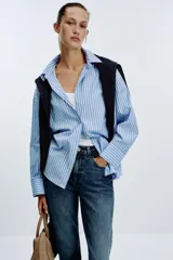 Pantalón de jean azul de tiro alto, corte mom fit, tobillero y con cinco bolsillos. Cierre frontal con cremallera y botón.