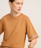 Blusa boxy de mangas cortas amplias, confeccionada en algodón, con cuello redondo y detalle de entremedios en las mangas.