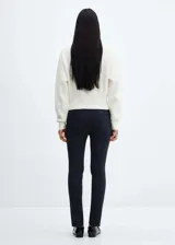 Pantalón negro de diseño crop, corte skinny y tiro medio. Cuenta con trabillas, dos bolsillos laterales, dos bolsillos de ribete en la parte posterior, cierre de cremallera y botón, y forro interior.
