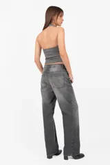 Top negro sin mangas con cuello halter, confeccionado en punto roma. Presenta escote embolsado con vista de algodón con lycra y elástico en su terminación para un mejor ajuste. Detalle de ojalillos color níquel en cuello y escote.
