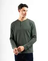 Remera de manga larga gris claro, confeccionada en tejido mini piqué de algodón. Presenta cuello redondo con abertura de tres botones.