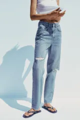 Pantalón de jean celeste de tiro alto, corte mom fit, largo regular y roturas en las rodillas.