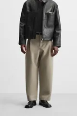 Pantalón negro de corte amplio tipo balloon fit, con cintura con pliegues frontales, bolsillos delanteros y traseros de plastrón. Cierre frontal con cremallera y botón.