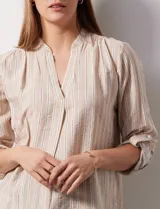 Blusa beige con rayas verticales blancas, escote en V y mangas 3/4 regulables con presilla y botón.