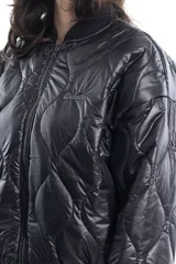 Campera bomber negra de tela satinada con cierre frontal, cuello redondo y puños y cintura elastizados. Tiene un pequeño logo bordado en el pecho y un bolsillo con cierre en la manga. Es reversible.