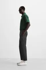 Pantalón slim fit negro confeccionado en tejido con elasticidad en ambas direcciones. Cuenta con bolsillos frontales y traseros de vivo con botón. Cierre frontal con cremallera y botón.