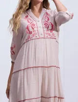 Vestido midi color crudo con bordados florales en el canesú y las mangas. Tiene cuello en V, mangas 3/4 y corte escalonado en la falda.