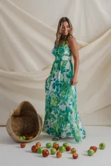 Vestido largo de gasa estampado con flores en tonos verde y blanco. Diseño cruzado con escote en V, sin mangas y falda con volados. Incluye faja en la cintura.