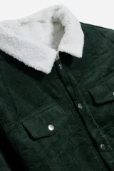 Campera verde de pana con cuello de corderito blanco, cierre con botones a presión, bolsillos con solapa en el pecho y bolsillos laterales.