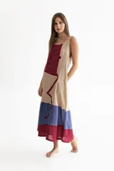 Vestido largo de lino color beige, con paneles en color rojo y azul. Diseño sin mangas, con escote cuadrado y bolsillos laterales.