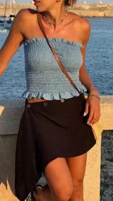 Minifalda negra de lino con corte irregular y cierre frontal con botones.