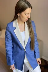 Blazer de lino color blanco con solapas y cuello en color beige, corte entallado, botón de nácar, tajo en la espalda y bolsillos laterales.
