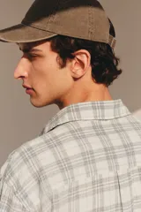Camisa blanca con diseño a cuadros grises, de corte holgado, manga larga y cuello inglés.