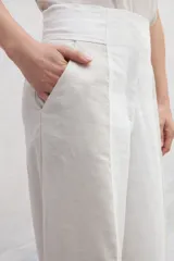 Pantalón de lino de tiro alto, con corte amplio a la cintura, confeccionado en dos colores: azul marino y marrón. Presenta un recorte delantero que estiliza la silueta. De calce cómodo.