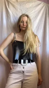 Top negro de cuero con tirantes finos de cuero sintético con argollas metálicas.