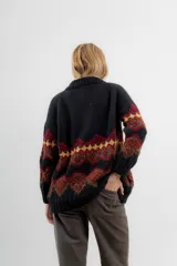 Saco de lana y poliamida color negro con diseño geométrico en tonos marrón, rojo y amarillo. Tiene silueta recta, largo debajo de la cola, bolsillos en los costados y escote polera con botones en todo el largo.