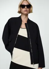 Chaqueta bomber negra con cierre frontal y bolsillos laterales.