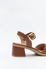 Sandalia negra de cuero sintético con pulsera al tobillo y hebilla metálica cuadrada. Presenta una capellada ancha que cubre el empeine y taco medio ancho.