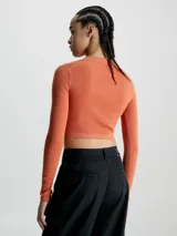 Sweater cropped color naranja de lyocell con textura de canalé, cuello polo en pico, mangas largas e insignia con el monograma de Calvin Klein en el bajo.