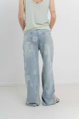 Pantalón de jean celeste de tiro alto y corte ancho, con bordado de flores grandes en hilo blanco hueso.