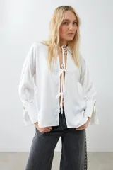 Camisa color crudo de tela satinada con lazos en el escote y mangas largas.