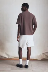 Remera marrón de punto calado suave, con cuello redondo y corte estándar.